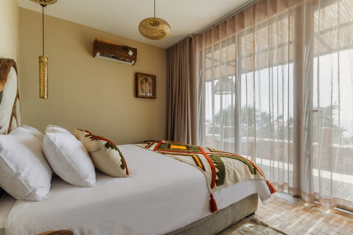 Chambre d'un bungalow privé Amanblu : lit double, tête de lit en noyer sculpté et grande baie vitrée